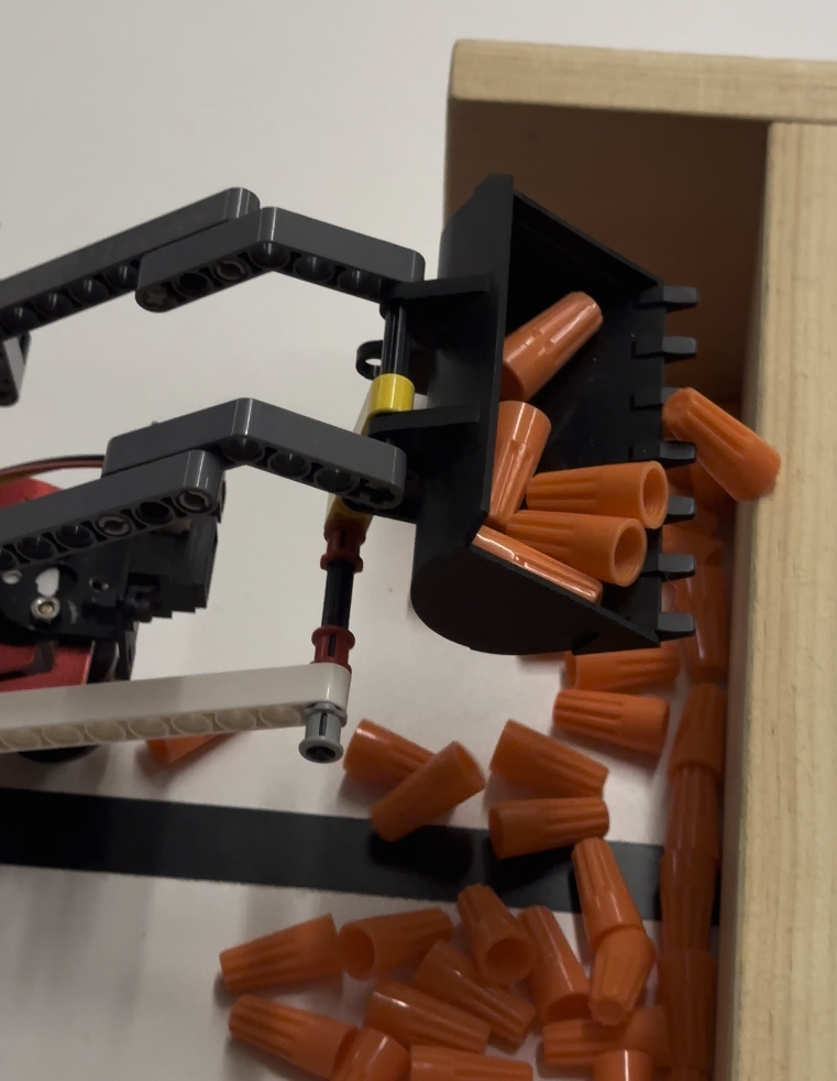 Close-up of the skidsteer's claw mechanism picking up wire nuts used as track objects