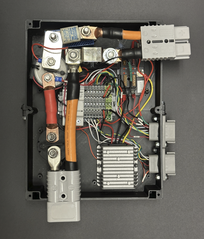 Interior of the custom electrical box, showing the battery disconnect, fuse, terminal blocks, DC-DC converter, and Anderson connectors