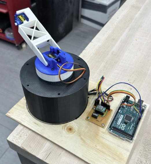 Early prototype of the arm base with a single servo joint and gripper, wired to an Arduino Mega on a workbench